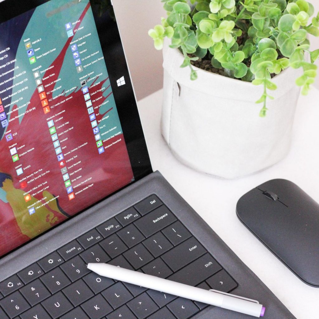 A laptop with list of apps on a desk.